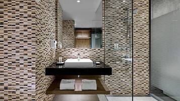 A modern bathroom with a tiled backsplash, a freestanding sink, and a glass shower enclosure.