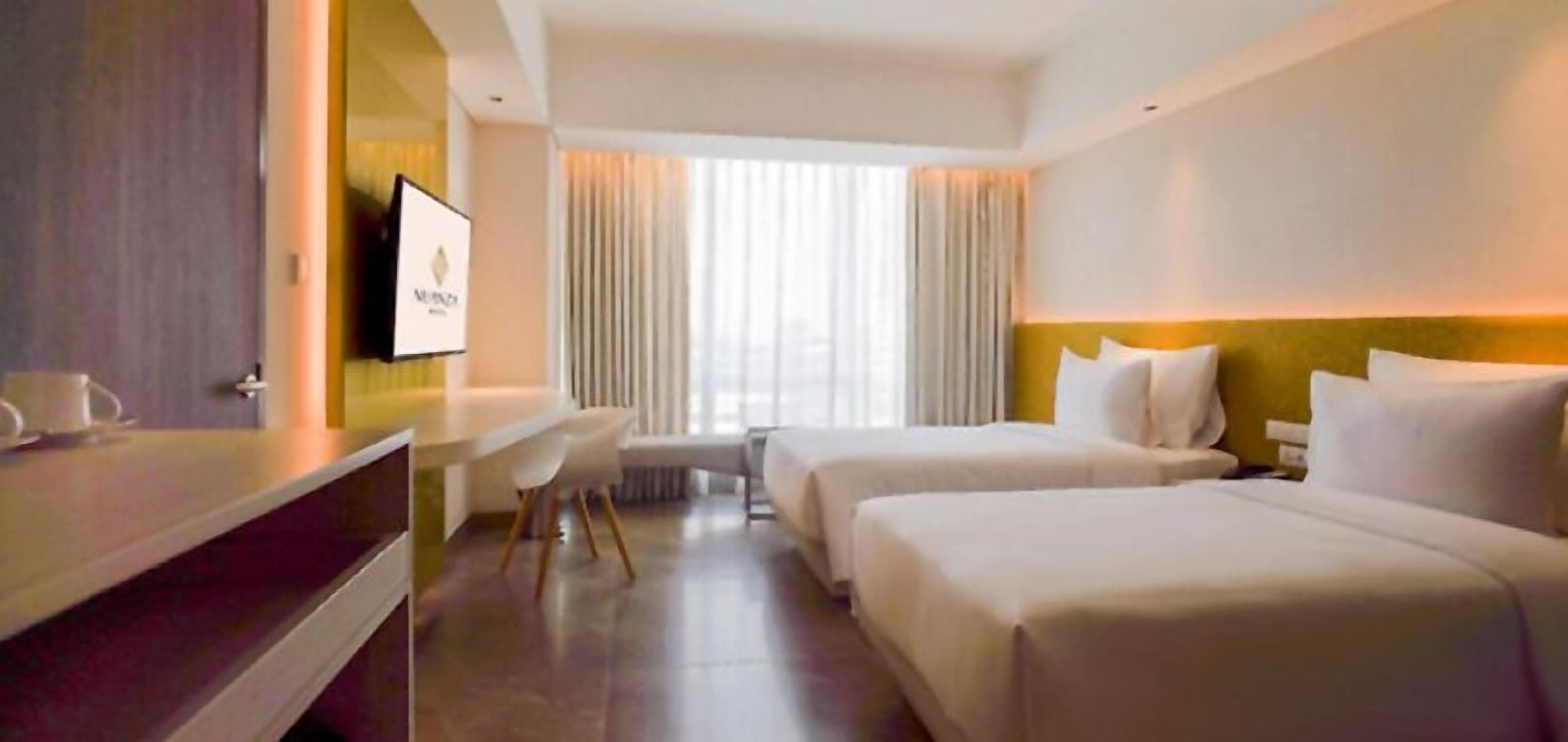 Ein Hotelzimmer mit zwei Betten, einem Schreibtisch und einem Fernseher.