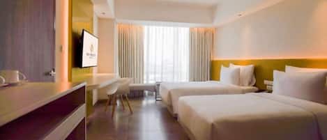 A hotel room with two beds, a desk, and a television.