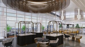 Una cafetería moderna con una amplia ventana que ofrece vistas a un paisaje urbano, con una barra central y zonas de estar.
