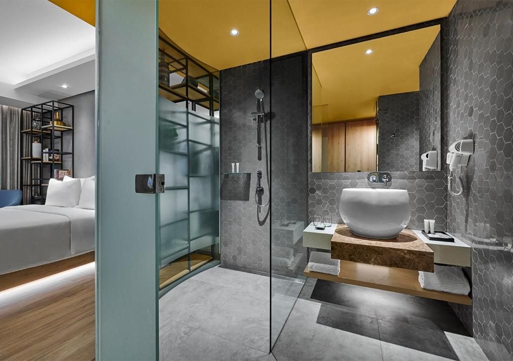 Un baño moderno con ducha envuelta en vidrio, un lavabo de diseño y un mueble de tocador de madera.