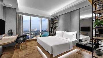 Een moderne hotelkamer met een groot bed, een bureau, een stoel, een televisie en een boekenplank.