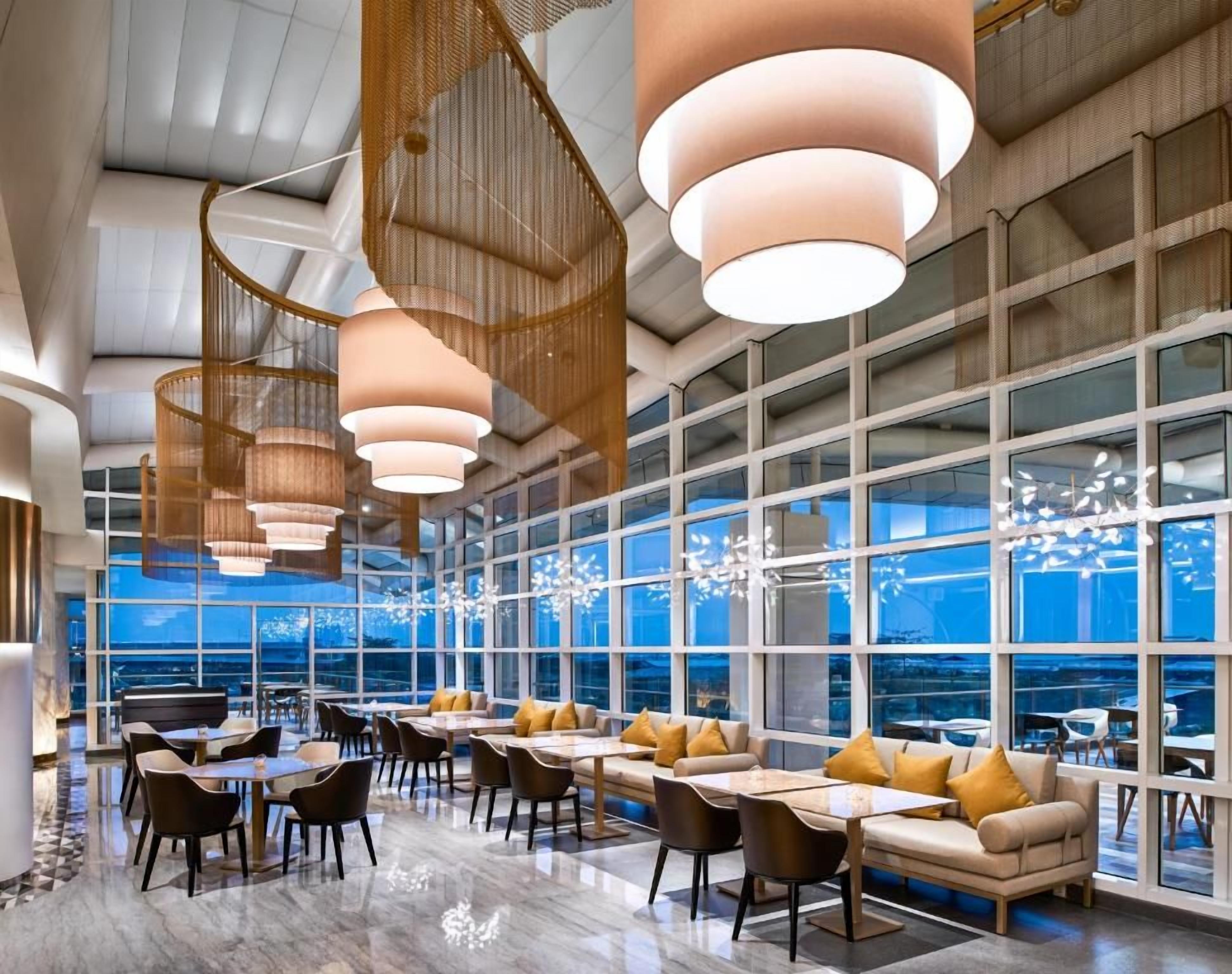Un interior moderno con comedor, ventanas amplias y lámparas colgantes.