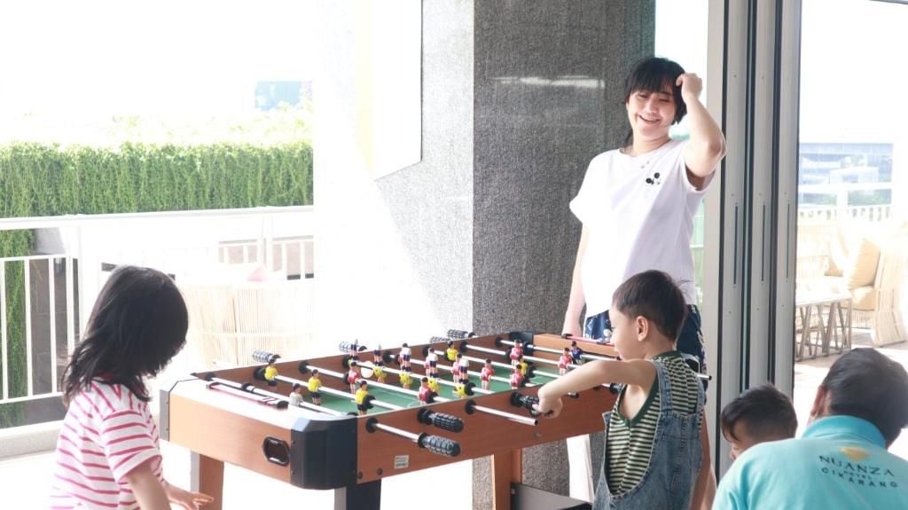 A group of people playing foosball outdoors with a table and players visible.