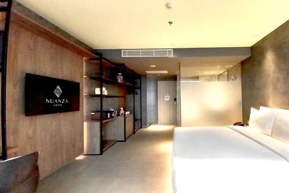 Une chambre d’hôtel moderne dotée d’un grand lit, d’un téléviseur fixé au mur et d’une bibliothèque intégrée.