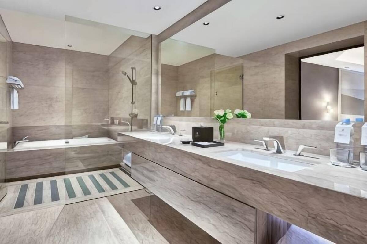 Une salle de bain moderne avec un grand miroir, deux lavabos, une baignoire et une douche.