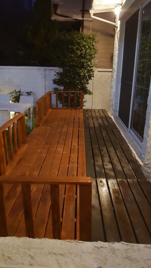 A wooden deck with a bench, a railing, and a potted plant.