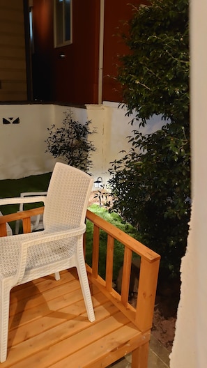 A white wicker chair on a wooden deck with a small garden area, including a bush and a lantern. - The standard apartment shibuya B (Tokyo)