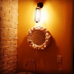 A bathroom with a brick wall, a round sink, and a wall-mounted light fixture. - The standard apartment shibuya D (Tokyo)