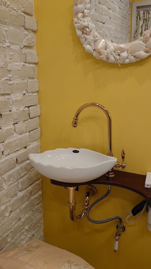 A bathroom with a white sink, gold faucet, and a decorative mirror with seashells. - The standard apartment shibuya D (Tokyo)