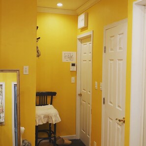A narrow hallway with yellow walls, white doors, and a small table with a white cloth. - The standard apartment shibuya D (Tokyo)