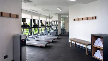 A gym with treadmills, a water dispenser, a bench, and a towel rack.