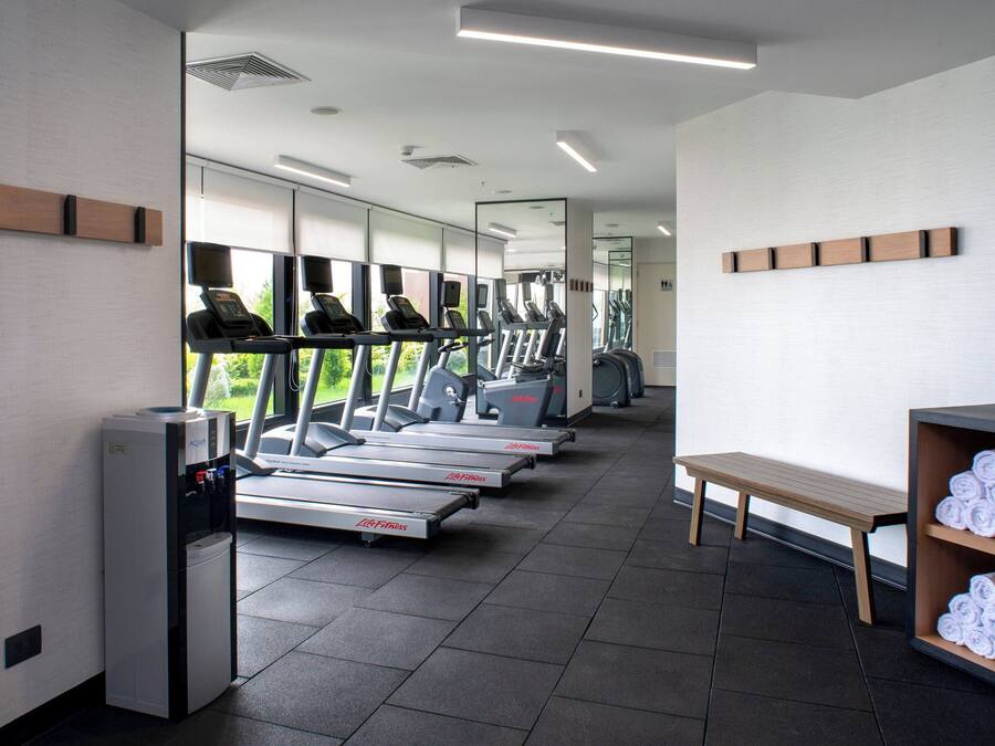 A gym with treadmills, a water dispenser, a bench, and a towel rack.