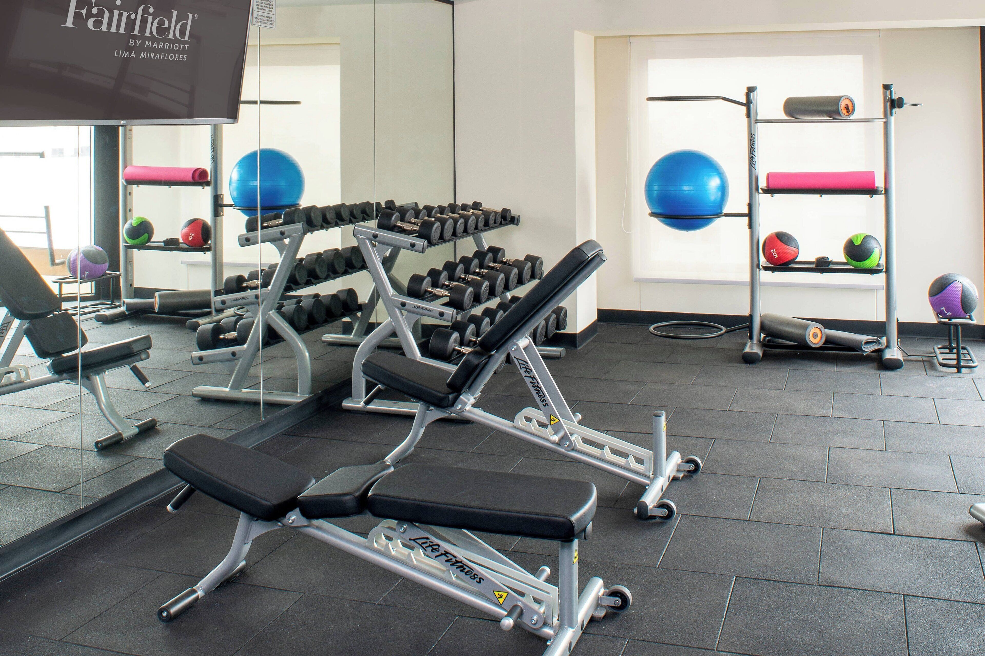 A gym with weight machines, dumbbells, and exercise balls.