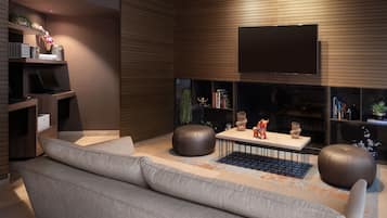 Ett modernt vardagsrum med en soffa, sittpallar, ett soffbord och en platt-TV som är monterad på väggen.