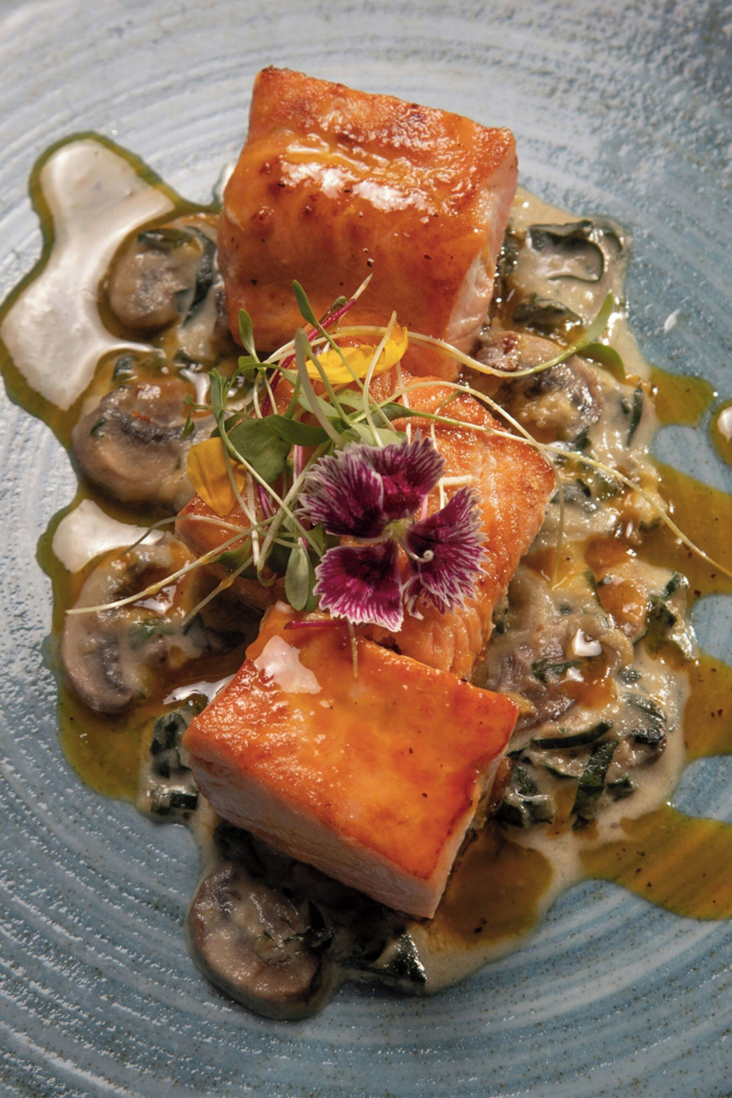 Prato com salmão, cogumelos e vegetais verdes.