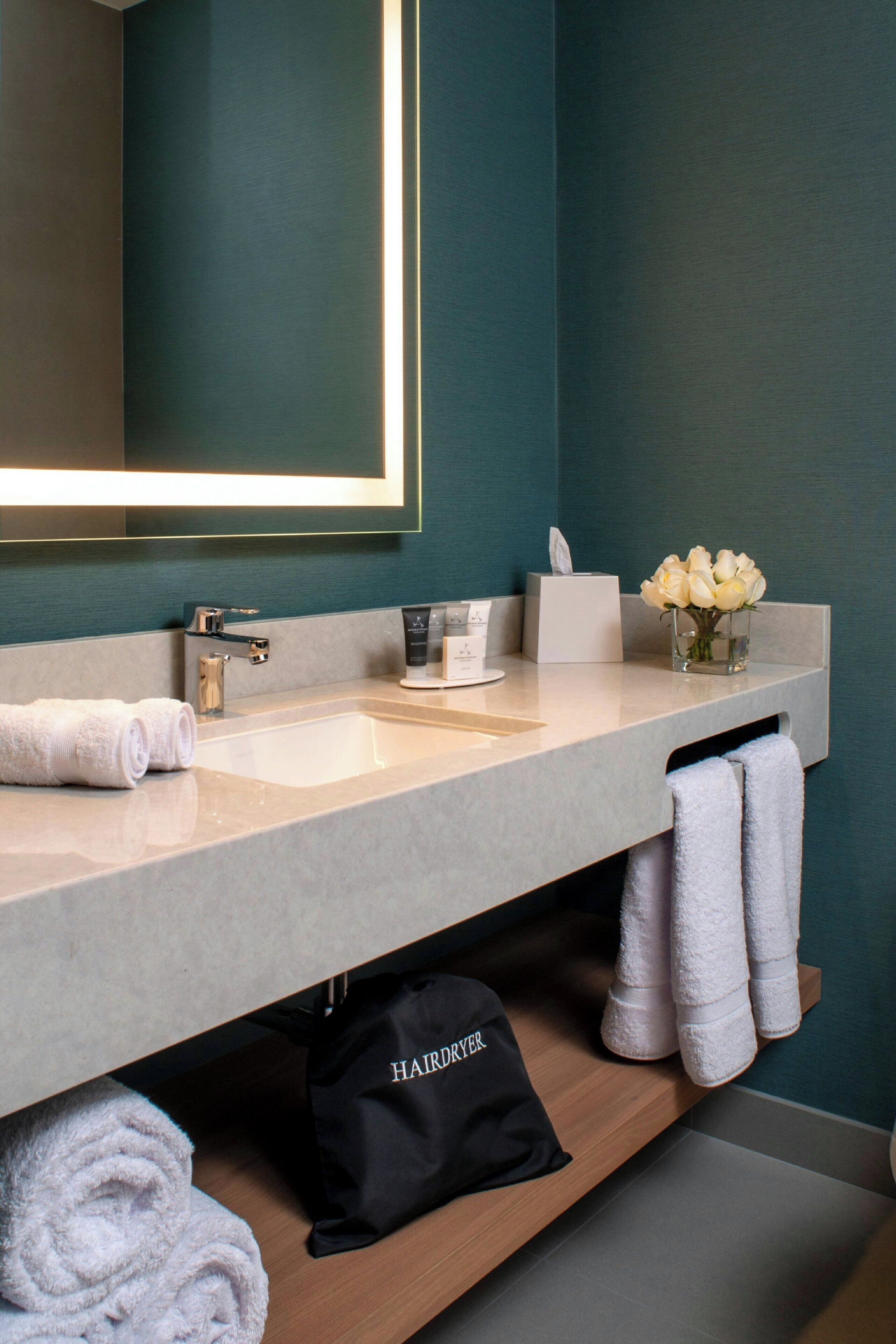 A modern bathroom with a large mirror, a sink, and a towel rack.