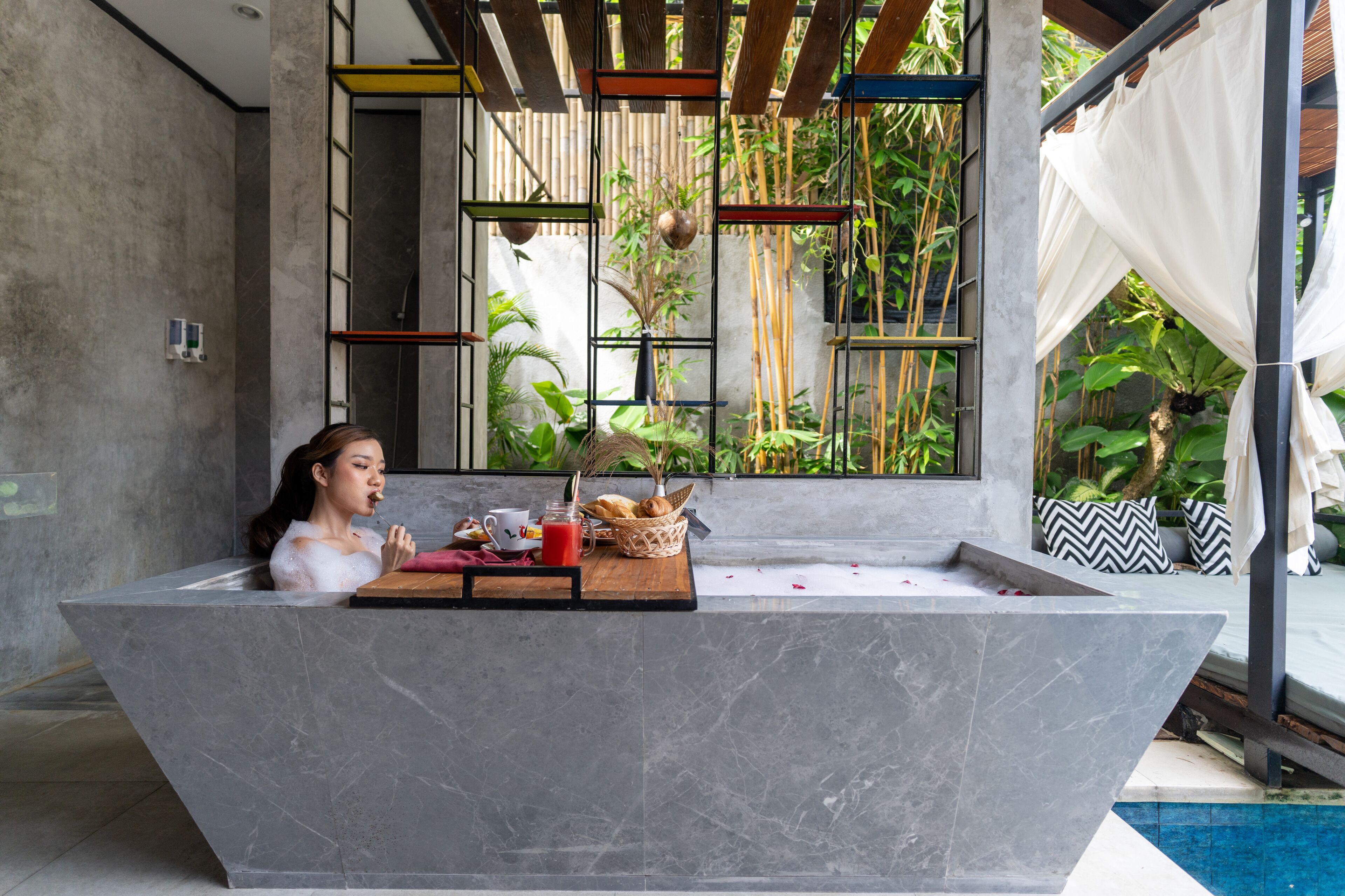 Une salle de bain moderne avec un lavabo en marbre, une fenêtre ornée de plantes en bambou et une vue sur l’extérieur.