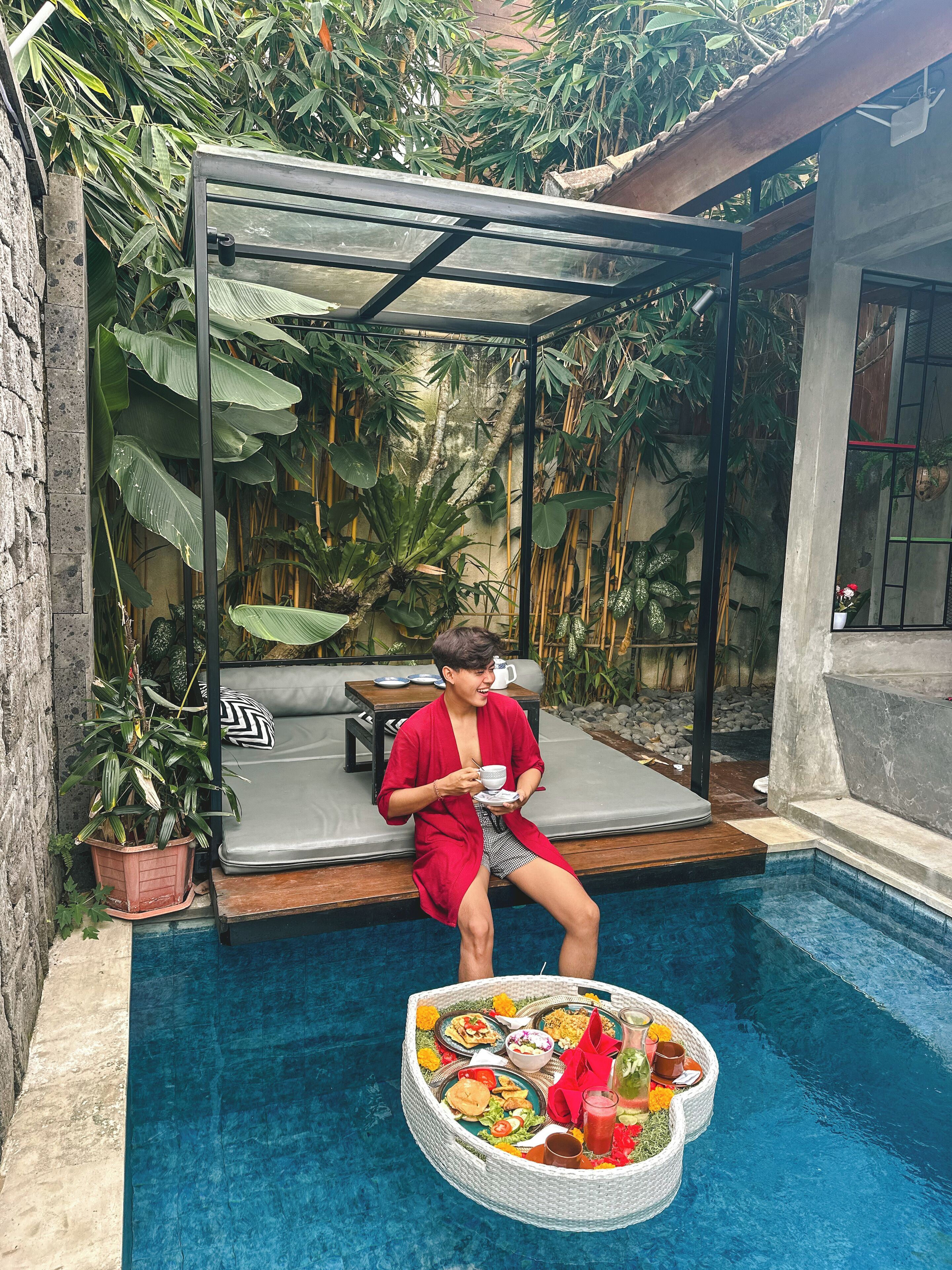 A person sitting by a poolside with a dining setup.