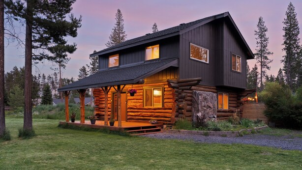 A log cabin with a porch, a stone wall, and a well-maintained lawn. - Cascade Getaway, Hot Tub, Fenced Acre, Pet Friendly (Bend)