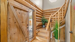 A wooden staircase with a rustic design, a door with a metal grid, and a potted plant. - Cascade Getaway, Hot Tub, Fenced Acre, Pet Friendly (Bend)