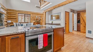 A spacious kitchen with a marble countertop, wooden cabinets, and a red towel hanging on the oven. - Cascade Getaway, Hot Tub, Fenced Acre, Pet Friendly (Bend)