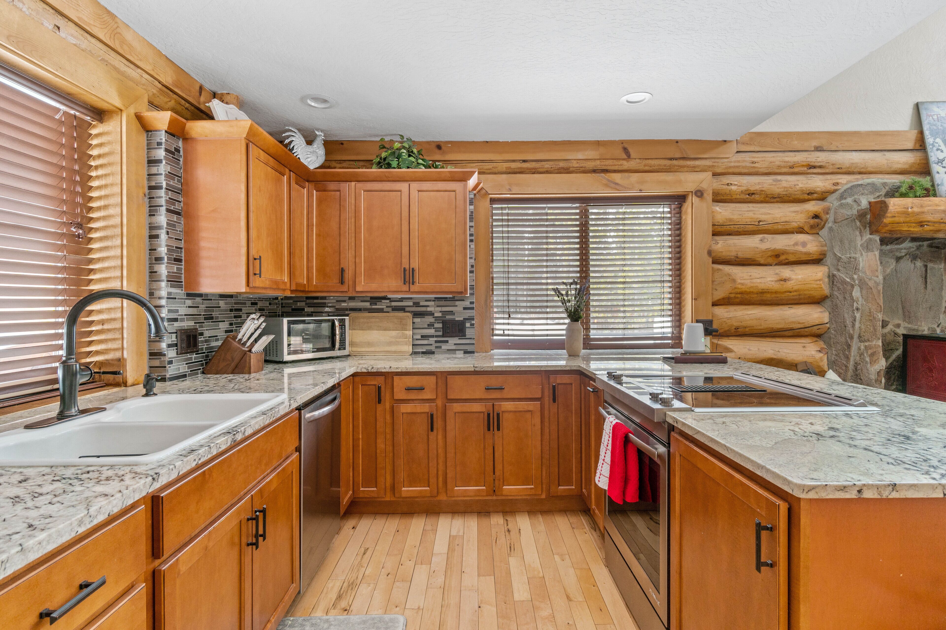 A modern kitchen with wooden cabinets, granite countertops, and a stone backsplash.