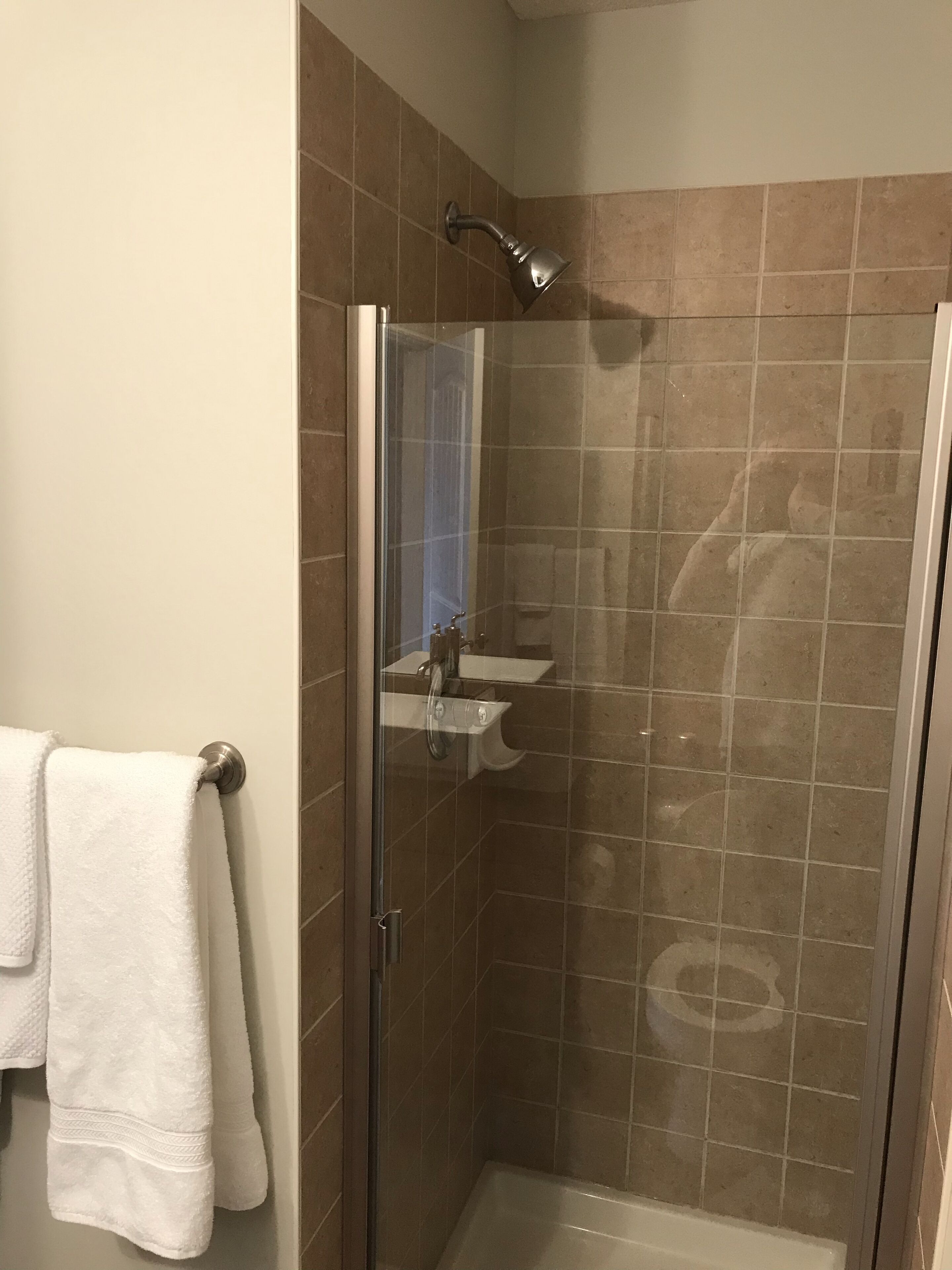 Une douche avec une porte en verre, un lavabo blanc et un porte-serviettes.