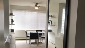 A modern living room with a white sofa, a dining table with chairs, and a large mirror. - 2 BR, 2 BA Newly Renovated Condo with Pool (Calgary)