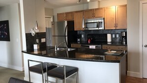 A modern kitchen with a central island, stainless steel appliances, and wooden cabinets. - 2 BR, 2 BA Newly Renovated Condo with Pool (Calgary)