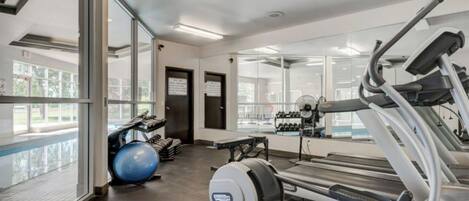 Een sportschool met loopbanden, fitnessballen en een spiegelwand.