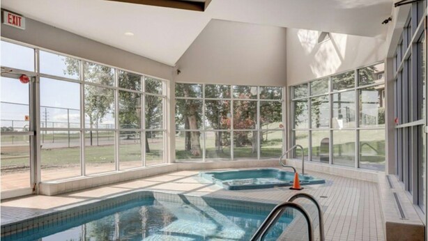 A swimming pool with clear glass walls, a tiled floor, and an exit sign. - 2 BR, 2 BA Newly Renovated Condo with Pool (Calgary)