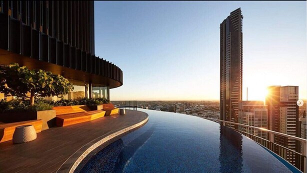 A rooftop infinity pool with a city view, modern architecture, and a sunset. - Executively Inspired - 2 Bed 2 Bath Apt on Queen St with Carpark Fast WiFi Rooftop Pool and Sleeps 5 (Brisbane City)