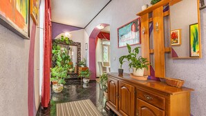Un pasillo con un mueble de madera, plantas en macetas y obras de arte en las paredes.