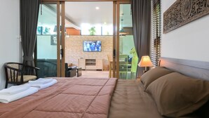 A hotel room with a bed, a TV, a sofa, a chair, and a table. - Nice House Pool Villa Phuket (Chalong)