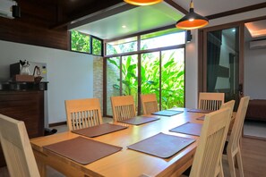 Un comedor con una mesa de madera, sillas y un amplio ventanal con vistas a zonas verdes.