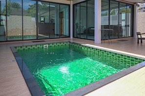 Uma piscina interior moderna com paredes de vidro e um deck de madeira.