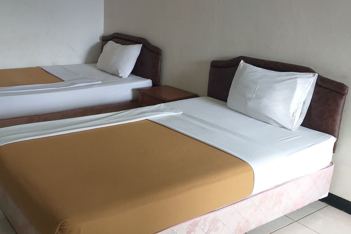 Une chambre d’hôtel avec deux lits simples et un lit double.