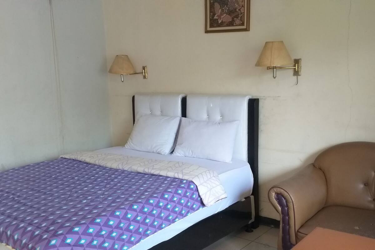 Une chambre à coucher avec un lit, une chaise et deux lampes fixées au mur.