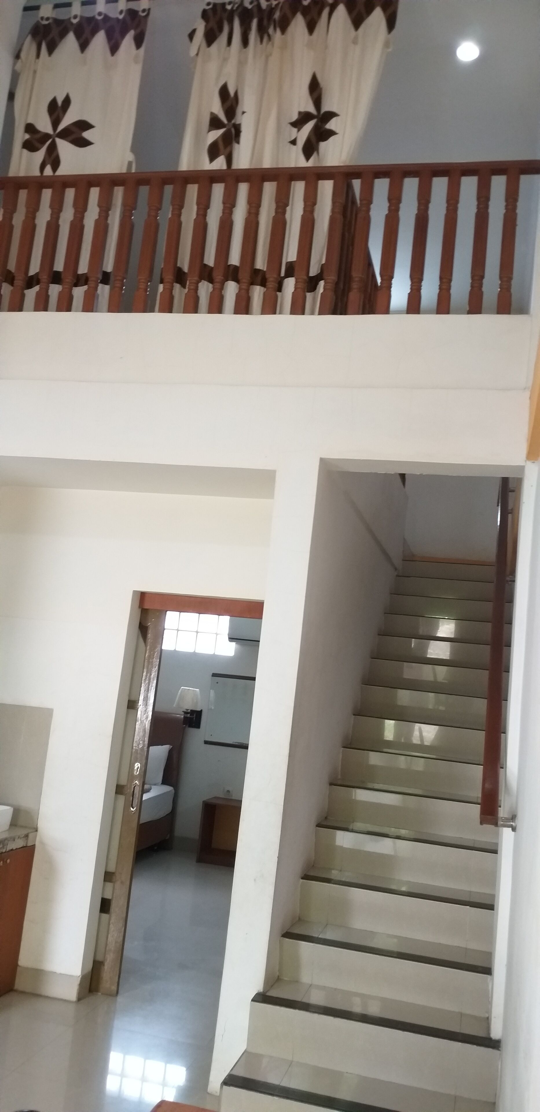 A staircase with a wooden handrail leading to a second-floor balcony.