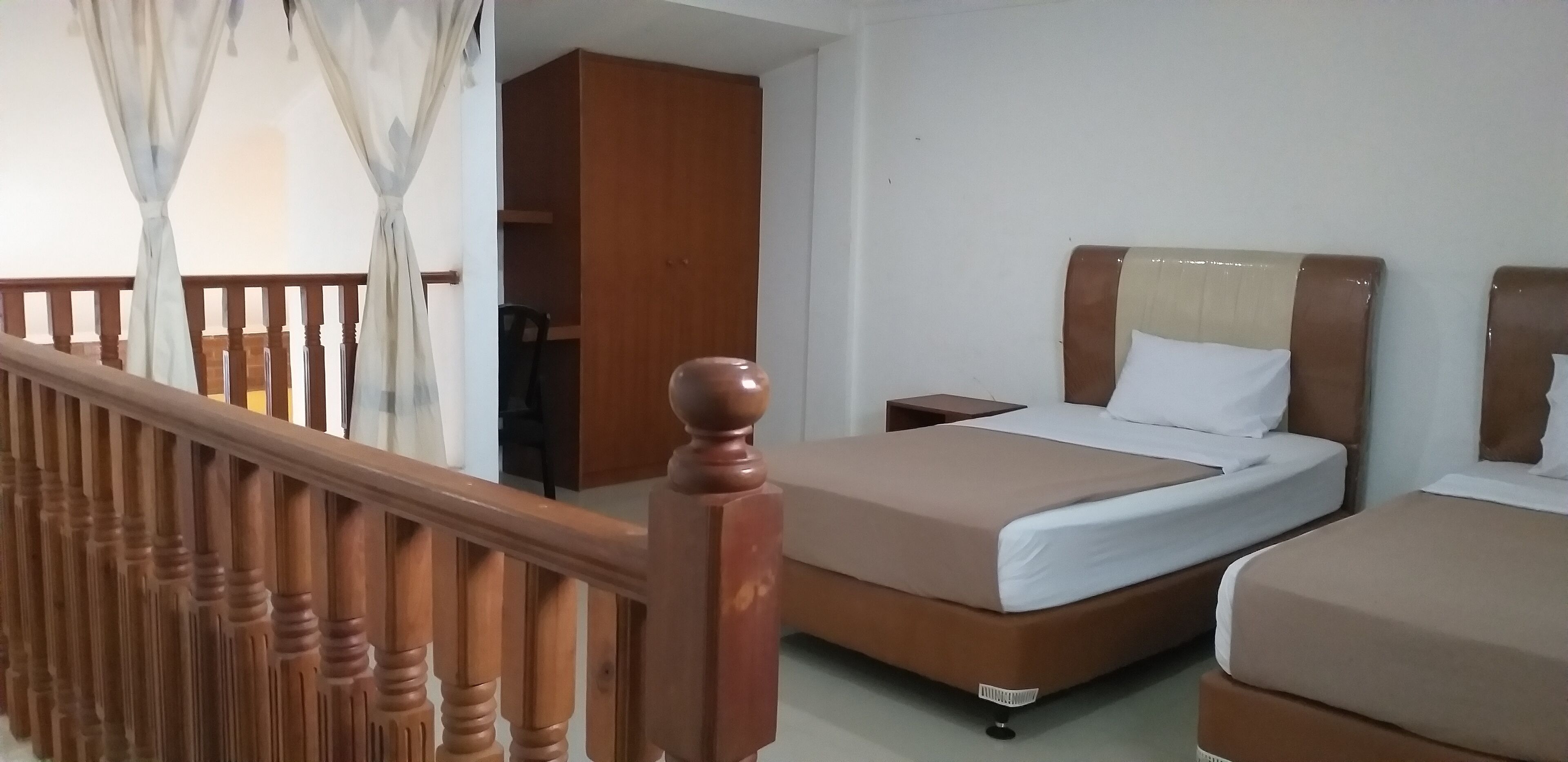 A hotel room with a wooden staircase, a bed with a headboard, and a wardrobe.