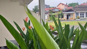 Une vue d’un bâtiment avec un toit rouge et des murs blancs, entouré de verdure et d’autres bâtiments.