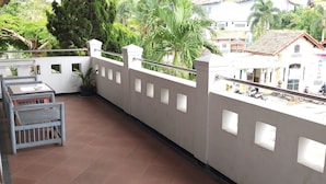 Un balcon avec un sol carrelé, une balustrade et un pot de fleurs.