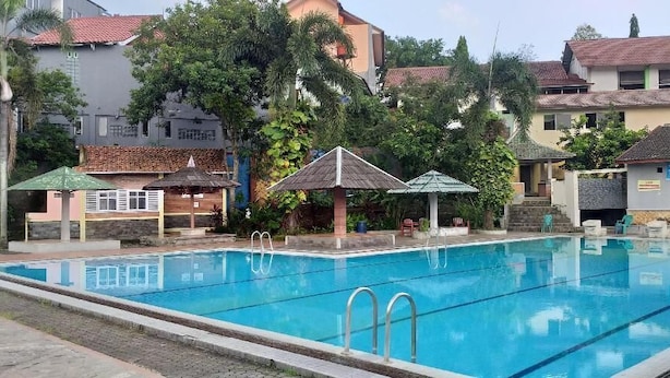 Une piscine dotée de deux plongeoirs, entourée d’immeubles et d’arbres.