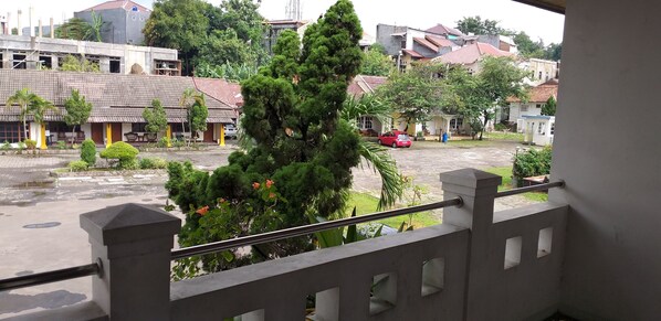 A courtyard with a red car parked, surrounded by buildings with red-tiled roofs and some greenery.