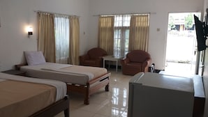 Une chambre d’hôtel avec deux lits, une petite table, deux chaises et un réfrigérateur.