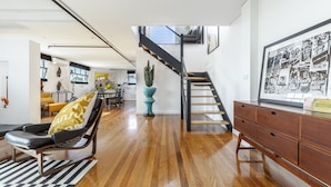 Un vaste espace de vie doté d’un plancher en bois, d’un escalier moderne et d’un coin repas situé à l’arrière-plan.