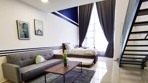 A modern living room with a grey sofa, a coffee table, and a staircase. - Ekocheras Serviced Apartment by Duke Homes (Kuala Lumpur)