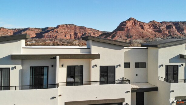 Un bâtiment moderne à plusieurs étages, doté d’un toit plat et de grandes fenêtres, qui se détache sur un paysage de formations rocheuses rouges.