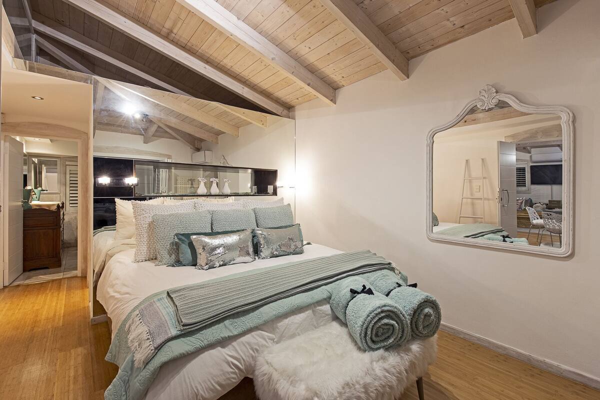 Ein Schlafzimmer mit Bett, Spiegel und Holzboden.